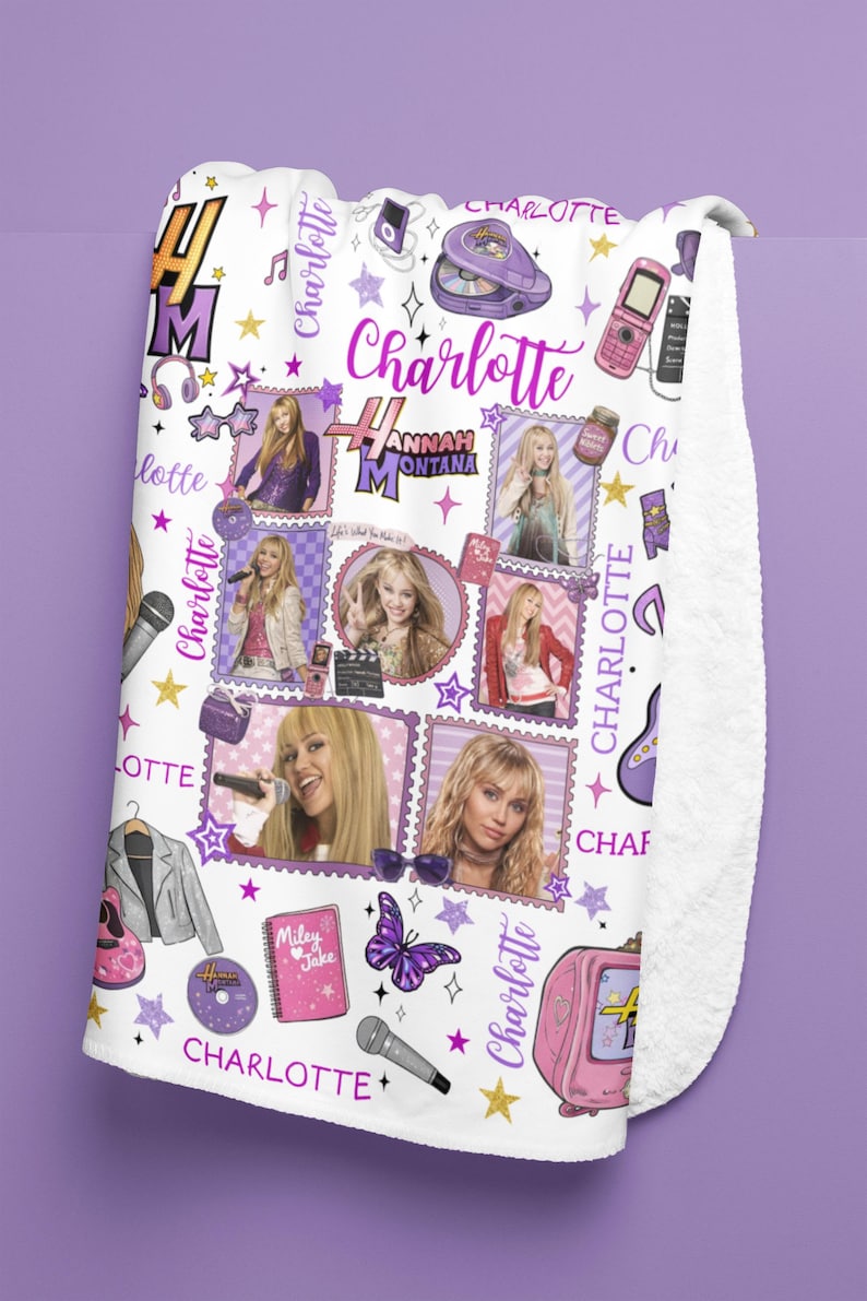 May include: White fleece blanket featuring a collage of images and text related to the character Hannah Montana. The design includes photos, stars, and the name "Charlotte" in various fonts and colors. A pink television and a butterfly are also visible.