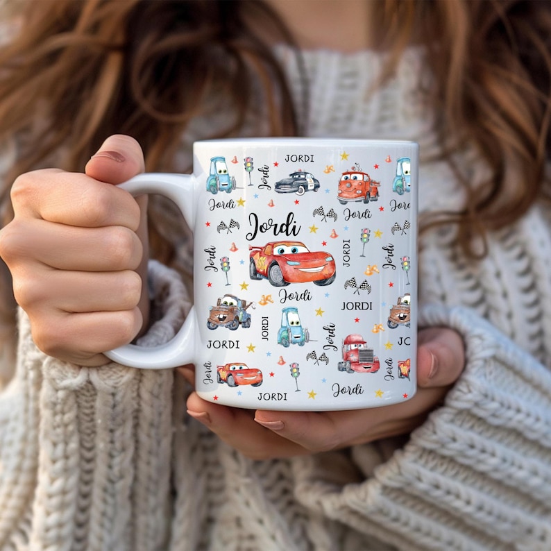 May include: A white ceramic mug with a black handle and the text "But First, Coffee" in a black, handwritten-style font. The mug is on a white surface.