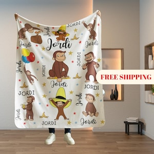 May include: A white blanket featuring cartoon illustrations of a monkey, bananas, stars, and the name "Jordi" in various fonts. The blanket has a repeating pattern of the monkey character in different poses.