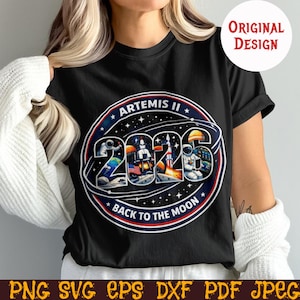 May include: Black t-shirt with a circular graphic featuring the text "ARTEMIS II 2026 BACK TO THE MOON." The design includes astronauts, a rocket, and the American flag. The words "ORIGINAL DESIGN" are in a white circle.