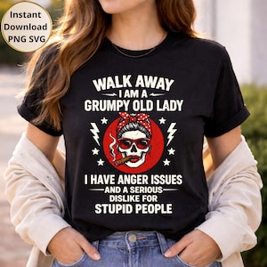 Könnte beinhalten: Schwarzes T-Shirt mit dem Text "WALK AWAY I AM A GRUMPY OLD LADY". Das Shirt zeigt eine Totenkopf-Grafik mit Sonnenbrille und rotem Bandana, die eine Zigarre hält. Der Text "I HAVE ANGER ISSUES AND A SERIOUS DISLIKE FOR STUPID PEOPLE" ist ebenfalls aufgedruckt.