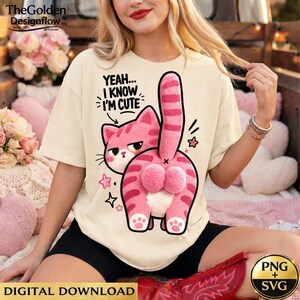 May include: Cream-colored t-shirt featuring a pink cat graphic with the text "YEAH... I KNOW I'M CUTE". The cat is depicted from the rear, with its tail and fluffy bottom prominently displayed. Additional star graphics are scattered around the cat.