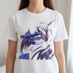 May include: White t-shirt featuring a colorful anime illustration of a female character with white hair, wings, and a sword. The character is wearing blue and purple clothing. The graphic is centered on the shirt.