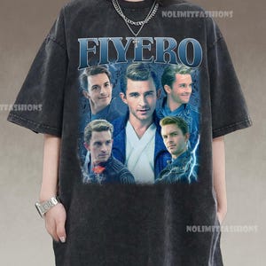 May include: Dark gray t-shirt featuring the word "FIYERO" in blue, with a collage of images of a man. The shirt has a vintage, washed look. The brand name "NOLIMITFASHIONS" is printed on the shirt.