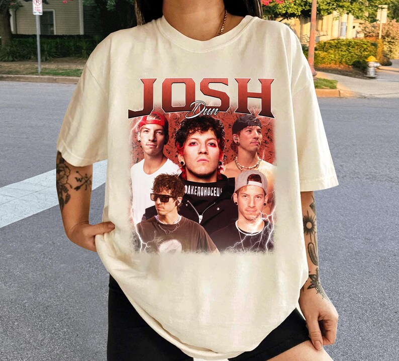 May include: Cream-colored t-shirt featuring a graphic of the band "Josh Dun" with a vintage design. The design includes images of the band members. The text "Josh Dun" is in a bold, red font.