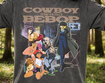 May include: Dark gray t-shirt featuring the text "COWBOY BEBOP" above a colorful anime graphic. The graphic depicts several characters in a futuristic city setting, with a dog and various figures in the foreground.