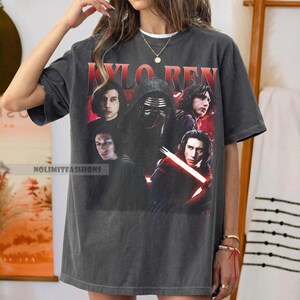 May include: Dark gray t-shirt featuring a graphic of Kylo Ren from Star Wars. The design includes multiple images of the character, with the name "KYLO REN" in red block letters at the top. The shirt has the text "NOLIMITFASHIONS" at the bottom.