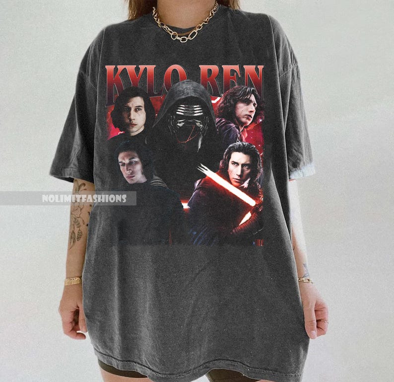 May include: Dark gray t-shirt featuring a graphic of Kylo Ren and other characters from the Star Wars film series. The text "KYLO REN" is printed in red at the top. The shirt has a vintage, worn look.