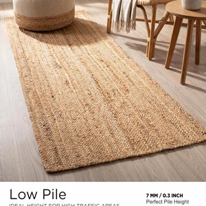 May include: A rectangular runner rug crafted from natural tan woven fibers with a braided texture. The rug features a low pile construction with a thickness of 0.3 inches, providing a flat surface suitable for placement in various indoor floor areas.