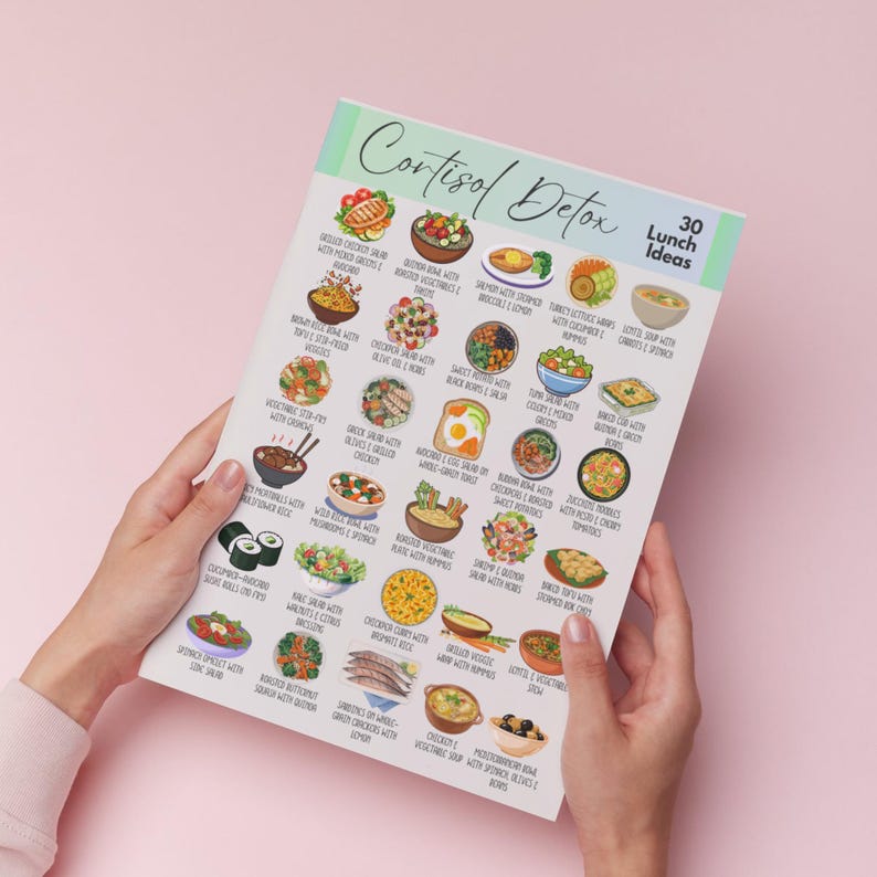 K&ouml;nnte beinhalten: Ein gedruckter Ratgeber mit dem Titel "Cortisol Detox" mit 30 Mittagsideen. Der Ratgeber enth&auml;lt farbenfrohe Illustrationen verschiedener gesunder Mahlzeiten, darunter Salate, Suppen und Bowls. Der Ratgeber wird von einer Person vor einem rosa Hintergrund gehalten.