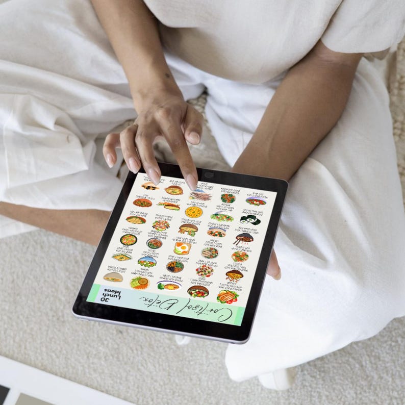 K&ouml;nnte beinhalten: Ein Tablet mit einer farbenfrohen Illustration von 30 Mittagsideen. Das Tablet wird von einer Person in wei&szlig;er Kleidung gehalten. Der Text "Cortisol Detox" und "30 Lunch Ideas" ist auf dem Bildschirm zu sehen.
