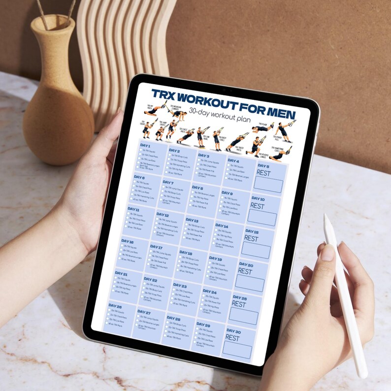 May include: A digital tablet displaying a 30-day TRX workout plan for men. The screen features a header with the text TRX WORKOUT FOR MEN, followed by a series of small illustrations showing exercise positions and a grid detailing daily routines.