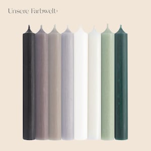 Könnte beinhalten: Acht schlanke Kerzen in verschiedenen Farben, darunter Schwarz, Lila, Grau, Weiß und Grün. Der Text "Unsere Farbwelt:" ist oben zu sehen. Diese Kerzen eignen sich für die Inneneinrichtung und besondere Anlässe.