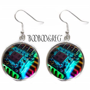 May include: A pair of silver-toned drop earrings featuring circular glass cabochons. The inserts display a vibrant, high-contrast digital circuit board pattern with glowing blue, green, and red hues. The text *BOOBOO&REG* is centered above.