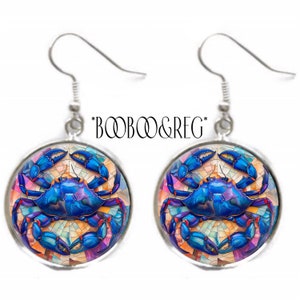 May include: A pair of silver dangle earrings featuring a blue crab with a mosaic design. The crab is surrounded by a colorful mosaic pattern.