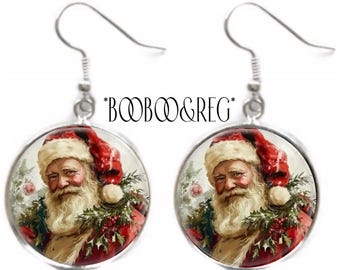 May include: A pair of round dangle earrings featuring a vintage-style illustration of Santa Claus with a white beard, red hat, and green holly accents. The silver-toned metal settings include hook-style ear wires. The text *BOOBOO&REG* is centered.