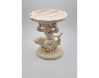 Jabonera vintage MCM Holland Mold con diseño de niño querubín sobre pedestal de delfín, color arena moteada.