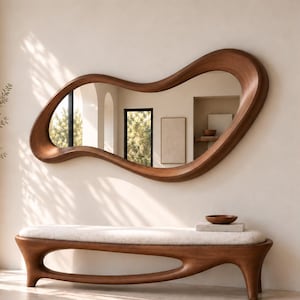 May include: A wall-mounted mirror with an irregular, organic wooden frame featuring a smooth, curved shape. Below it sits a matching wooden bench with a cream-coloured upholstered seat, supported by a continuous, fluid base design.