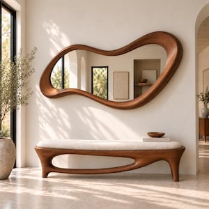 May include: A large, horizontal wall mirror with an irregular, organic wooden frame featuring a smooth, warm brown finish. Below the mirror sits a long bench with a thick, cream-coloured upholstered seat and a curved, solid wood base.