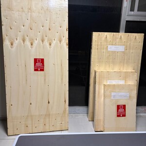 May include: Four rectangular wooden shipping crates of varying sizes, each constructed from light-coloured plywood. Each crate features a red square label with white text reading MIRROR PRODUCT SENSITIVE FRAGILE KEEP VERTICAL and an upward arrow.