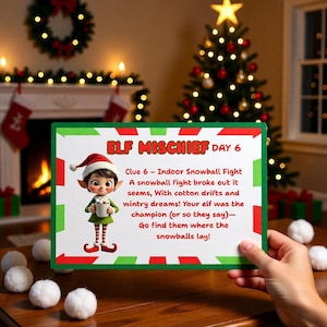 Puede incluir: Un letrero verde y blanco con el texto "ELF MISCHIEF DAY 6" y una ilustración de un elfo de dibujos animados. El letrero se sostiene frente a un árbol de Navidad y una chimenea, con bolas de nieve blancas.
