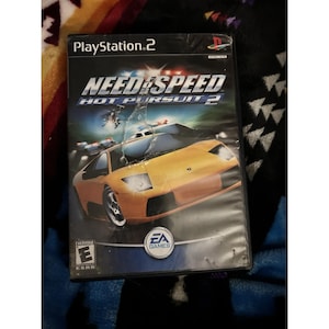 May include: A PlayStation 2 game case for "Need for Speed: Hot Pursuit 2." The cover features a bright yellow sports car with police cars in the background. The EA Games logo is visible, along with the ESRB rating.