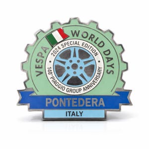 Könnte beinhalten: Ein Vespa World Days 2024 Special Edition Pin. Der Pin hat einen hellgrünen, zahnradförmigen Rand mit dem Text "VESPA WORLD DAYS" und "2024 SPECIAL EDITION". Er zeigt ein blau-weißes Raddesign, die italienische Flagge und den Text "PONTEDERA ITALY".