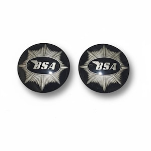 May include: Two black circular emblems featuring the silver text "BSA". Each emblem has a silver starburst design around the text. The BSA logo is in a black oval shape with a silver wing design.