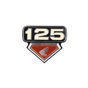 May include: A motorcycle emblem with the number "125" in white against a black background. Below the number is a red diamond shape with a silver wing emblem, a classic design.
