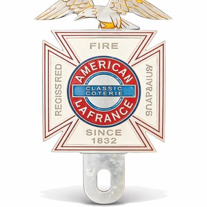 Può includere: Un emblema vintage in metallo con un design a croce bianca con bordi rossi, le parole "AMERICAN LAFRANCE CLASSIC COTERIE" e "SINCE 1832". Un'aquila con accenti dorati e bianchi è in cima all'emblema.