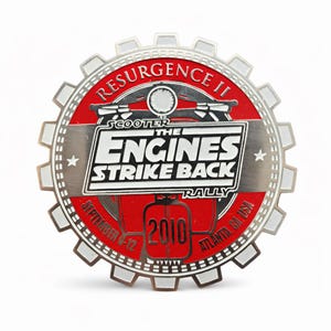 May include: A round, metallic pin with a gear-like border. The pin features the text "RESURGENCE II" and "THE ENGINES STRIKE BACK RALLY". The year "2010" is displayed, along with "ATLANTA, GA, USA" and "SEPTEMBER 4-12".