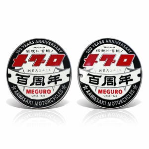 May include: Two round black and white Kawasaki Meguro motorcycle emblems. The emblems feature the text "100 Years Anniversary" and "470" in red. The text "Meguro Since 1924" is also visible.