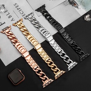 Op de afbeelding: Vier metalen horlogebanden in roségoud, goud, zilver en zwart. Elke band heeft een schakelkettingontwerp. De banden worden weergegeven op een zwarte ondergrond, met een roségouden horlogekast zichtbaar linksonder.