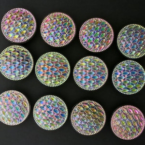 May include: Twelve iridescent glass buttons with a scalloped edge and a pattern of overlapping ovals. The buttons are various shades of blue, green, and purple.