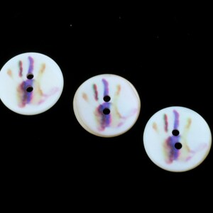 May include: Three white buttons with a colorful handprint design. Each button has two holes.