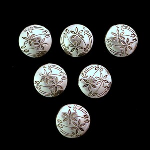May include: Six silver buttons with a floral design. The buttons are round and have a raised design of flowers and leaves.