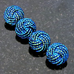 May include: Five iridescent blue and green glass beads with a spiral design.