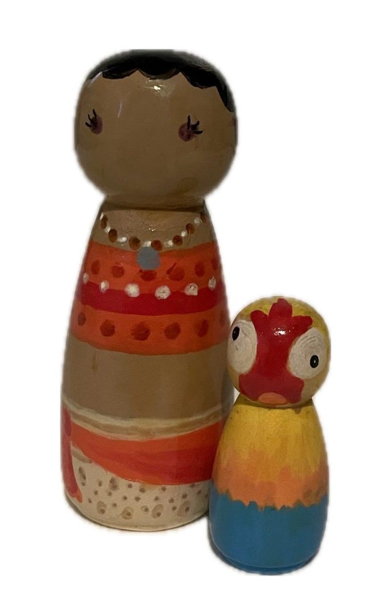May include: Two hand-painted wooden peg dolls. The larger doll has brown skin, black hair, and is wearing an orange and red dress. The smaller doll has a yellow, orange, and blue body with a red face. Decorative items.