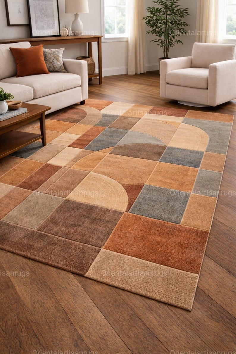 Op de afbeelding: Vloerkleed met geometrisch patroon in bruin-, beige- en grijstinten. Het vloerkleed heeft een modern design met vierkanten, rechthoeken en gebogen vormen. Het vloerkleed ligt op een parketvloer, in een woonkamer.