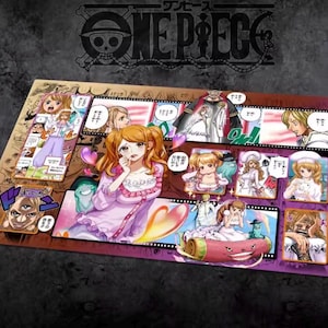 May include: A rectangular playmat with vibrant anime-style character illustrations. The playmat has a dark background with the "ONE PIECE" logo at the top. The illustrations are in a comic strip format with speech bubbles and Japanese text.