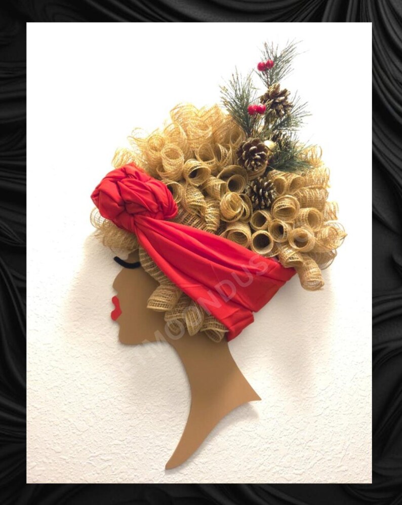 May include: A wall decoration depicting a woman's profile with a red headscarf and gold-coloured curly hair. The hair is decorated with pine cones, berries, and evergreen sprigs. The woman has red lips.