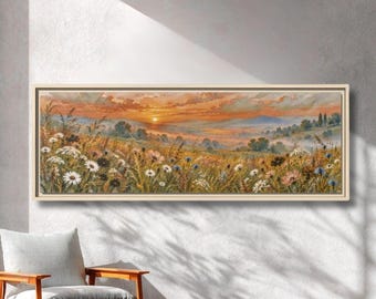 Könnte beinhalten: Ein panoramisches Landschaftsgemälde in einem hellen Holzrahmen, das ein Feld mit Wildblumen unter einem Sonnenuntergangshimmel zeigt. Die Szene umfasst weiße Gänseblümchen, blaue Kornblumen und hohes Gras mit Hügeln und Bäumen im Hintergrund.