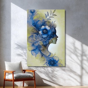 Puede incluir: Impresión artística en lienzo que muestra el perfil de una mujer adornado con diseños florales azules. La obra presenta una vista lateral con detalles intrincados, sobre un fondo amarillo pálido. Las flores y el follaje son en tonos azules y dorados.