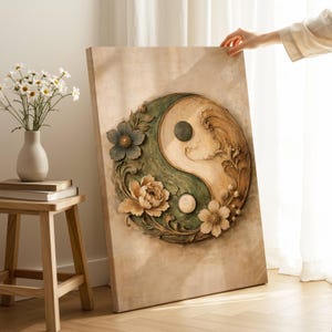 Puede incluir: Una gran obra de arte en lienzo que presenta el símbolo del Yin y Yang, adornado con detalles florales. El símbolo está dividido en secciones verdes y beige, con un diseño de olas en el lado beige. La obra de arte presenta flores texturizadas.