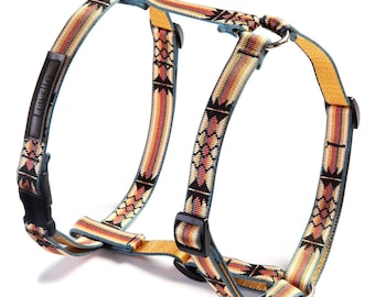 May include: A dog harness with a colorful geometric pattern in shades of orange, yellow, and teal. The harness has a black buckle and a metal ring for leash attachment. The brand name "Luvello" is visible on a black label.