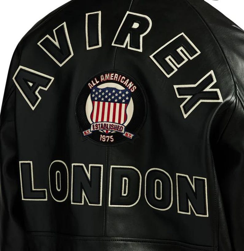 May include: Black leather jacket with white embroidered lettering spelling "AVIREX" and "LONDON". A circular patch features the American flag and the words "ALL AMERICANS ESTABLISHED 1975 N.Y."
