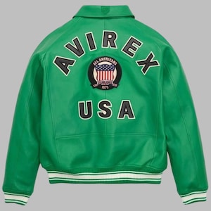 May include: Green leather jacket with the word "AVIREX" arched across the back in white lettering. Below the word "AVIREX" is a circular patch with the American flag and the words "ALL AMERICANS ESTABLISHED 1975". The word "USA" is below the patch.