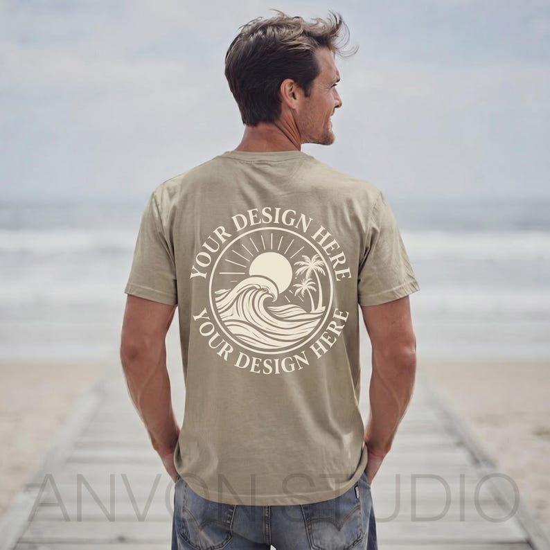May include: A khaki-colored t-shirt with a circular graphic on the back featuring a sun, waves, and palm trees. The text "YOUR DESIGN HERE" is printed around the graphic. The shirt is being worn by a person on a beach.