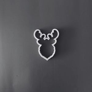 Op de afbeelding: Een witte plastic koekjesvorm in de vorm van een rendierkop met opvallend gewei. De vorm heeft een strakke, doorlopende omtrek die het silhouet van het gezicht van het dier en het vertakte gewei in een eenvoudige vorm weergeeft.