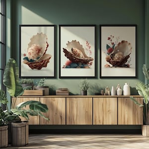 Puede incluir: Tres impresiones artísticas enmarcadas con ilustraciones de conchas marinas. Cada impresión muestra una representación detallada de una concha abierta con perlas y detalles florales. La obra de arte está sobre un fondo neutro, enmarcada en negro y expuesta sobre un mueble de madera.